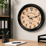 Wooden wall clock with black frame on a desk with office supplies. Metal wall clock 300mm