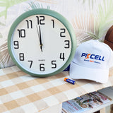 Wall clock with a Pixcell branded cap and battery on a table with a checkered tablecloth.