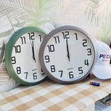 Two wall clocks on a surface with a cap and marker in the background.