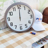 Wall clock on a table with a cap and battery in the background