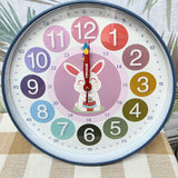 Children's wall clock with colorful numbers and a rabbit illustration on a textured surface. Educational clock with colorful hands and numbers on a white background time teacher 300mm wide