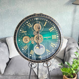 Decorative clock with intricate design on a stand against a neutral  Decorative clock with intricate design on a stand in a living room setting metal 600mm wide moving gears background