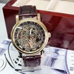 Gold wristwatch with brown leather strap on a decorative stand