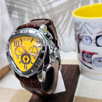 Watch with a yellow face and brown leather strap next to a mug with clock designs.