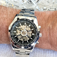 Silver wristwatch with a black face on a wrist, close-up view