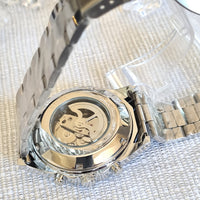 Close-up of a silver and gold watch with intricate design on a textured white background