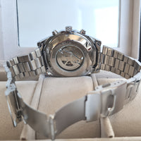 Silver watch with a detailed back view on a white cushion
