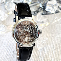 Mechanical watch with black leather strap on a sparkling background