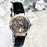 Mechanical watch with black leather strap on a sparkling background