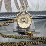 Vintage pocket watch with chain on a clear stand against a neutral background