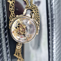 Gold pocket watch with intricate design on a chain against a blurred background