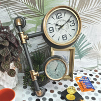 Decorative clock with pipes on a polka dot surface with plants and batteries.