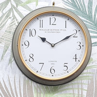 Round wall clock with gold frame and white face on a decorative background