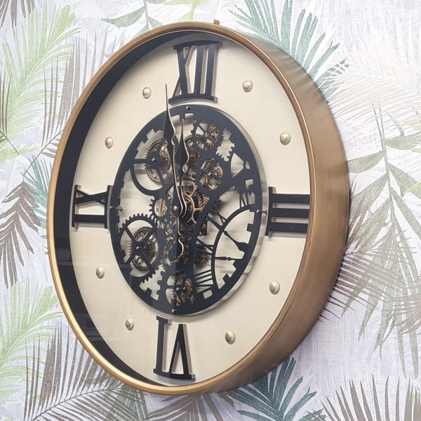 Decorative wall clock with brass frame and black Roman numerals on a leafy background