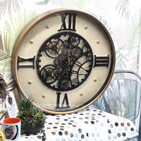 Decorative wall clock with mechanical gears on a table with a polka dot tablecloth.