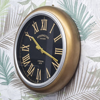 Gold and black clock with Roman numerals on a leaf-patterned background
