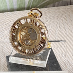 Gold pocket watch on a stand with a textured surface background