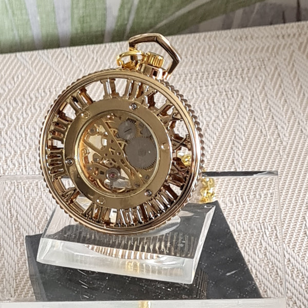 Gold pocket watch on a stand with a textured surface background