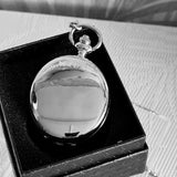 Silver pocket watch in a black box on a textured surface