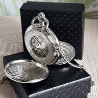 Silver pocket watch with chain on a black box