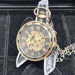 Gold pocket watch with Roman numerals on a black background