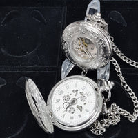 Silver pocket watch with open face on a black background