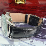 Close-up of a watch with a black leather strap on a decorative surface