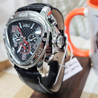 Luxury watch with black leather strap and silver case on a wooden stand.