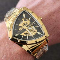 Gold wristwatch with a black face featuring a skull design on a person's wrist.