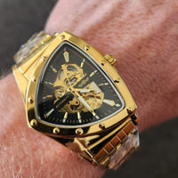Gold wristwatch with a detailed face on a wrist against a dark background