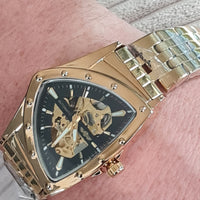 Gold wristwatch with a detailed face on a person's wrist.