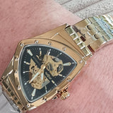 Gold wristwatch with a detailed face on a person's wrist.